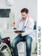 doctor writing prescription to disabled patient. Стоковое фото, агентство Ingram Publishing / Фотобанк Лори