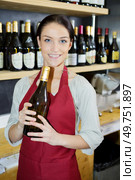 smiling female sommelier presenting a wine bottle. Стоковое фото, агентство Ingram Publishing / Фотобанк Лори