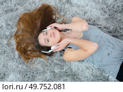 Woman layed on carpet listening to headphones. Стоковое фото, агентство Ingram Publishing / Фотобанк Лори