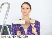 portrait of woman with roller and paintbrush dubious expression. Стоковое фото, агентство Ingram Publishing / Фотобанк Лори