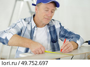 mature builder taking measures indoors. Стоковое фото, агентство Ingram Publishing / Фотобанк Лори