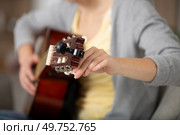 close-up of woman tuning a guitar. Стоковое фото, агентство Ingram Publishing / Фотобанк Лори