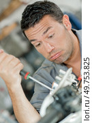 Mechanic using screwdriver, looking exhausted. Стоковое фото, агентство Ingram Publishing / Фотобанк Лори
