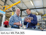 industrial manager holding tablet showing information to colleague. Стоковое фото, агентство Ingram Publishing / Фотобанк Лори