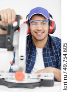 smiling man using a mitre saw. Стоковое фото, агентство Ingram Publishing / Фотобанк Лори
