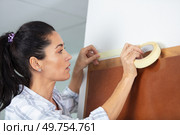 woman protecting wall with masking tape before painting. Стоковое фото, агентство Ingram Publishing / Фотобанк Лори