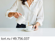 Женщина наливает чай в чашку на белом фоне / A woman pours tea into a cup on a white background. Стоковое AI-изображение, AI-художник Валерий Лукин / Фотобанк Лори
