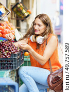 Vertical photo of a latin woman kneeling buying fresh fruits in a street shop. Woman kneeling buying fresh fruits in a street shop. Стоковое фото, агентство Ingram Publishing / Фотобанк Лори