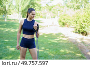 In the sunny park, a woman in activewear is using a resistance band for strength and conditioning exercises. She is effectively toning her body during this outdoor training session. A woman is exercising in a park with a resistance band on a sunny day, focusing on her fitness and wellbeing. Стоковое фото, агентство Ingram Publishing / Фотобанк Лори