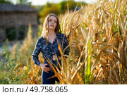 In a picturesque cornfield, a young woman stands gracefully, highlighting natures beauty in the warm evening light, dressed in a stylish outfit that reflects her unique personality. A Young Woman is Posing Gracefully in a Cornfield During the Beautiful Golden Hour Light. Стоковое фото, агентство Ingram Publishing / Фотобанк Лори