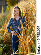 A young woman stands confidently in a vast cornfield, donning a chic and stylish outfit, perfectly complemented by the tall, golden stalks that surround her during a breathtaking sunset. A beautiful portrait of a young woman in a cornfield during a stunning sunset scene. Стоковое фото, агентство Ingram Publishing / Фотобанк Лори