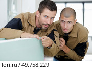 nervous workman pointing into the distance to show colleague. Стоковое фото, агентство Ingram Publishing / Фотобанк Лори