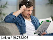 young man sitting doing a crossword puzzle. Стоковое фото, агентство Ingram Publishing / Фотобанк Лори