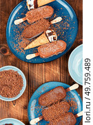 Portions of ice cream in chocolate glaze on wooden rustic background. Tasty glazed ice cream bars with nuts.. Vanilla ice cream with chocolate. Стоковое фото, агентство Ingram Publishing / Фотобанк Лори