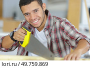 smily young workman using handsaw. Стоковое фото, агентство Ingram Publishing / Фотобанк Лори