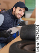 mechanic looking at clipboard in tyre in garage. Стоковое фото, агентство Ingram Publishing / Фотобанк Лори