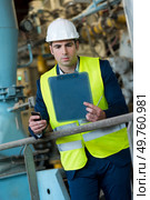 suited man in site holding clipboard and smartphone. Стоковое фото, агентство Ingram Publishing / Фотобанк Лори