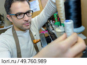Man changing cotton reel on machine. Стоковое фото, агентство Ingram Publishing / Фотобанк Лори