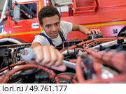 smiling automechanic repairs the engine of a lorry or bus. Стоковое фото, агентство Ingram Publishing / Фотобанк Лори