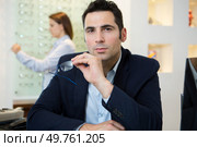 portrait of suited man holding eyeglasses in the opticians. Стоковое фото, агентство Ingram Publishing / Фотобанк Лори