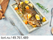 Appetizing trout fish baked in orange sauce and rosemary on a stylish stone serving board.. Baked or roasted trout fish. Стоковое фото, агентство Ingram Publishing / Фотобанк Лори