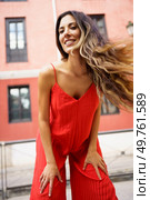 A confident woman poses gracefully in a vibrant red outfit, showcasing her flowing hair against a colorful backdrop, appealing to those who enjoy stylish and energetic photography. A Stylish Woman Dressed in a Vibrant Red Outfit with Beautiful Flowing Hair that Flows Gracefully. Стоковое фото, агентство Ingram Publishing / Фотобанк Лори
