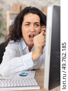 mature angry woman ready to break computer at the office. Стоковое фото, агентство Ingram Publishing / Фотобанк Лори
