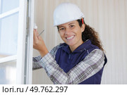 happy woman mounts the tilt and turn stopper on window. Стоковое фото, агентство Ingram Publishing / Фотобанк Лори