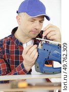carpenter changes the blade on an electric jigsaw. Стоковое фото, агентство Ingram Publishing / Фотобанк Лори