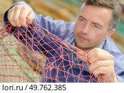 male worker is fixing the net. Стоковое фото, агентство Ingram Publishing / Фотобанк Лори
