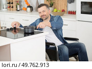 man on wheelchair cooking meal. Стоковое фото, агентство Ingram Publishing / Фотобанк Лори