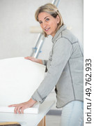 woman unrolling a wall paper on the wall. Стоковое фото, агентство Ingram Publishing / Фотобанк Лори