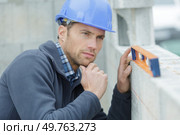 worker measures the curvature of the wall with a level. Стоковое фото, агентство Ingram Publishing / Фотобанк Лори