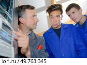 Man with apprentices pointing to thermostatic regulator. Стоковое фото, агентство Ingram Publishing / Фотобанк Лори