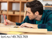 bearded handsome cabinetmaker at the tabletop with pencil. Стоковое фото, агентство Ingram Publishing / Фотобанк Лори