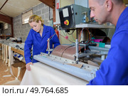 Man and woman unrolling material. Стоковое фото, агентство Ingram Publishing / Фотобанк Лори