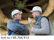 workers stood underneath industrial turbine. Стоковое фото, агентство Ingram Publishing / Фотобанк Лори