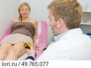 doctor performing electronic treatment to womans leg. Стоковое фото, агентство Ingram Publishing / Фотобанк Лори