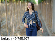 A carefree woman happily strolls through a picturesque vineyard on a beautiful, sunny day, wearing a stylish floral top with highwaisted jeans, exuding confidence, happiness, and a sense of fashion. A Joyful Woman Strolling Through a Picturesque Vineyard While Wearing a Beautiful Floral Outfit. Стоковое фото, агентство Ingram Publishing / Фотобанк Лори