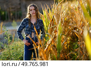 A young woman stands confidently posing amidst the towering corn stalks, beautifully capturing the true essence of rural life and the serene, picturesque beauty of the idyllic countryside setting. A stunning portrait captures a young womans beauty in a beautiful cornfield during the sunset. Стоковое фото, агентство Ingram Publishing / Фотобанк Лори