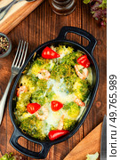 A delightful broccoli and shrimps casserole served in a deep ceramic dish on a wooden table.. Broccoli casserole with prawns. Стоковое фото, агентство Ingram Publishing / Фотобанк Лори