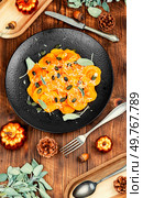 Pumpkin ravioli with herbs pumpkin seeds. Italian dinner on rustic wooden table. Cooking process.. Fall pumpkin ravioli drizzled with sage. Стоковое фото, агентство Ingram Publishing / Фотобанк Лори