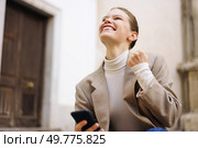 A young woman is joyfully celebrating an important achievement while holding her smartphone high, showcasing her overwhelming happiness and success in a lively and casual outdoor setting. A Joyful Young Woman is Celebrating with a Smartphone While Enjoying the Outdoors. Стоковое фото, агентство Ingram Publishing / Фотобанк Лори