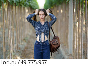 A playful young woman with charming pigtails poses joyfully in a beautiful vineyard, showcasing her trendy outfit and cheerful expression amidst the lovely scenery of nature all around her. A Playful Young Woman Joyfully Posing in a Beautiful Outdoor Vineyard Environment. Стоковое фото, агентство Ingram Publishing / Фотобанк Лори