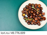 Cracked roasted chestnuts, roasted chestnuts some chestnuts split open , garnished with fresh rosemary, styled with autumn leaves. Copy space.. Charred roasted Chestnuts. Стоковое фото, агентство Ingram Publishing / Фотобанк Лори