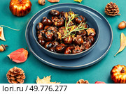 Cracked roasted chestnuts, roasted chestnuts some chestnuts split open , garnished with fresh rosemary, styled with autumn leaves.. Warm roasted chestnuts served on a plate. Стоковое фото, агентство Ingram Publishing / Фотобанк Лори