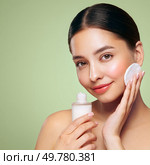 Young girl holds cotton pad while cleansing face with cosmetic milk. Skin care removal of makeup cleansing. Basic facial skin care. Стоковое фото, агентство Ingram Publishing / Фотобанк Лори