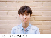 A vibrant young woman with a stylish short haircut shows surprise as she confidently poses against a lightbrick wall, embodying the emotion and diversity of contemporary urban life. A surprised young woman sporting a trendy short hairstyle stands against a neutral backdrop. Стоковое фото, агентство Ingram Publishing / Фотобанк Лори