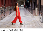A confident woman in a vibrant red outfit walks gracefully down a serene street, embodying the union of fashion and natural beauty, captivating everyone with her cheerful demeanor. A stylish woman enjoys a leisurely stroll in a bustling urban setting, exuding confidence. Стоковое фото, агентство Ingram Publishing / Фотобанк Лори