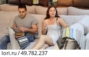 In store,husband and wife are sitting on gray sofa and choose upholstered furniture for living room. Стоковое видео, видеограф Яков Филимонов / Фотобанк Лори